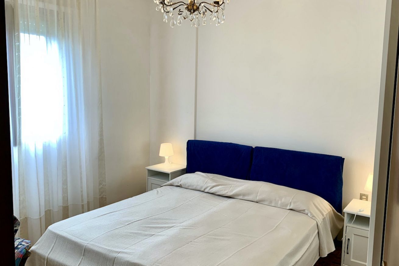 Una camera da letto con un letto, un comodino, una lampada e un lampadario.