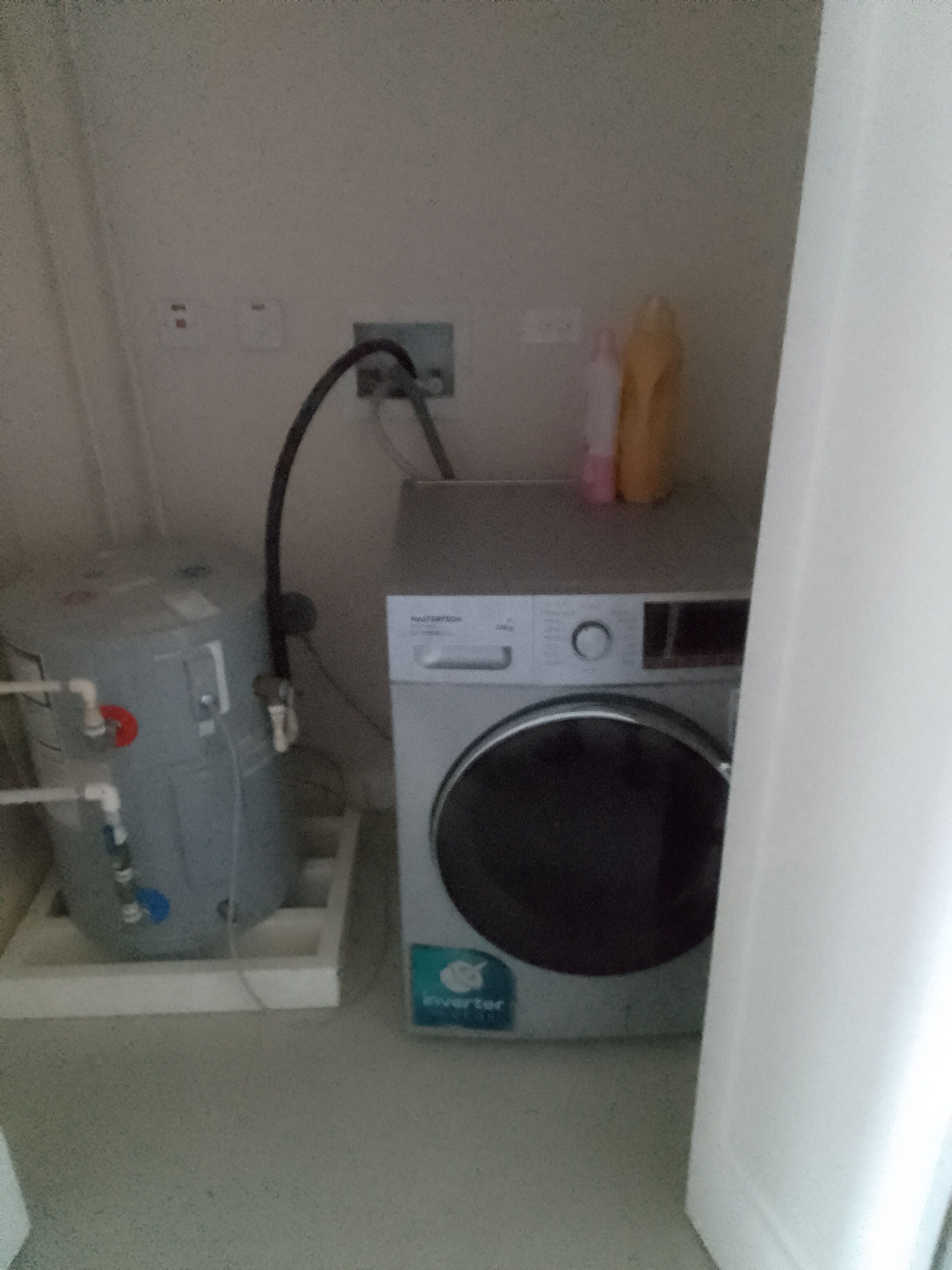 Een kleine wasruimte met een wasmachine en een boiler.