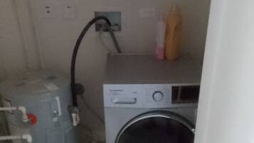 Een kleine wasruimte met een wasmachine en een boiler.