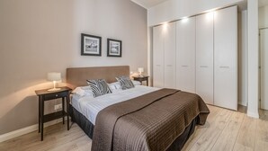 A bedroom with a bed, bedside tables, a wardrobe, and two framed pictures on the wall. - Apartments Florence - Borgo dei Greci (Firenze)