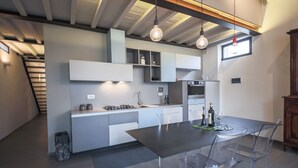 A modern kitchen with a dining area, featuring a large island, built-in cabinets, and pendant lighting. - Apartments Florence - Pepi Loft (Firenze)