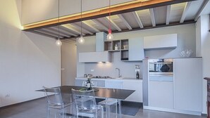 A modern kitchen with a dining area, featuring a central island, pendant lights, and built-in cabinetry. - Apartments Florence - Pepi Loft (Firenze)
