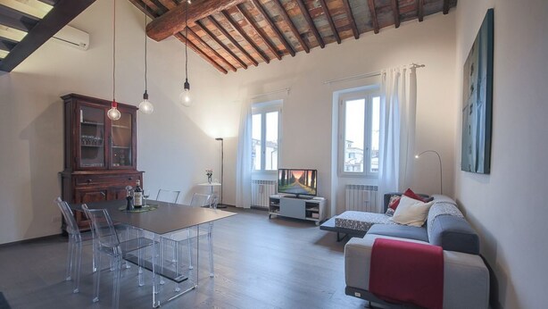 A spacious living area with a dining table, chairs, a sofa, and a television. - Apartments Florence - Pepi Loft (Firenze)