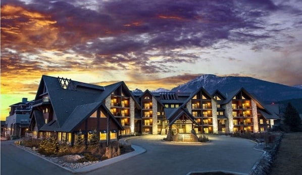 Situated in a mountainous region, this lodge features a central building with two wings, steeply pitched roofs, and a stone facade.