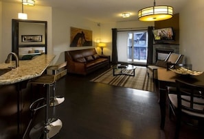 Relax in a stylish room with a sofa, dining area, and kitchenette, featuring a large window with an outside view and a fireplace.