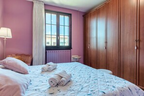 Un dormitorio con cama, ventana, radiador y armario.