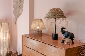 Une commode en bois, sur laquelle sont posés une lampe et une statuette d’éléphant décorative.