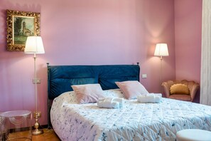 Ein Schlafzimmer mit einem Bett, zwei Nachttischlampen, einem Sessel und einem kleinen runden Tisch.