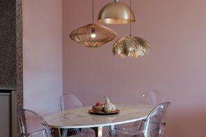 A dining area with a round table, clear chairs, and two hanging pendant lights.
