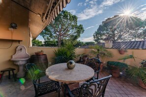 Eine Terrasse mit rundem Tisch, Stühlen, Kübelpflanzen und einer dekorativen Steinfountain.