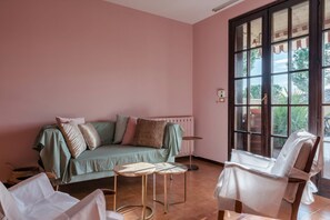 Une pièce chaleureuse avec un canapé vert, deux petites tables rondes et une chaise blanche.
