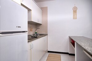 Modern kitchen with a refrigerator, sink, and granite countertop.