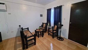 Une pièce avec un plancher en bois, une porte noire et un ventilateur de plafond.
