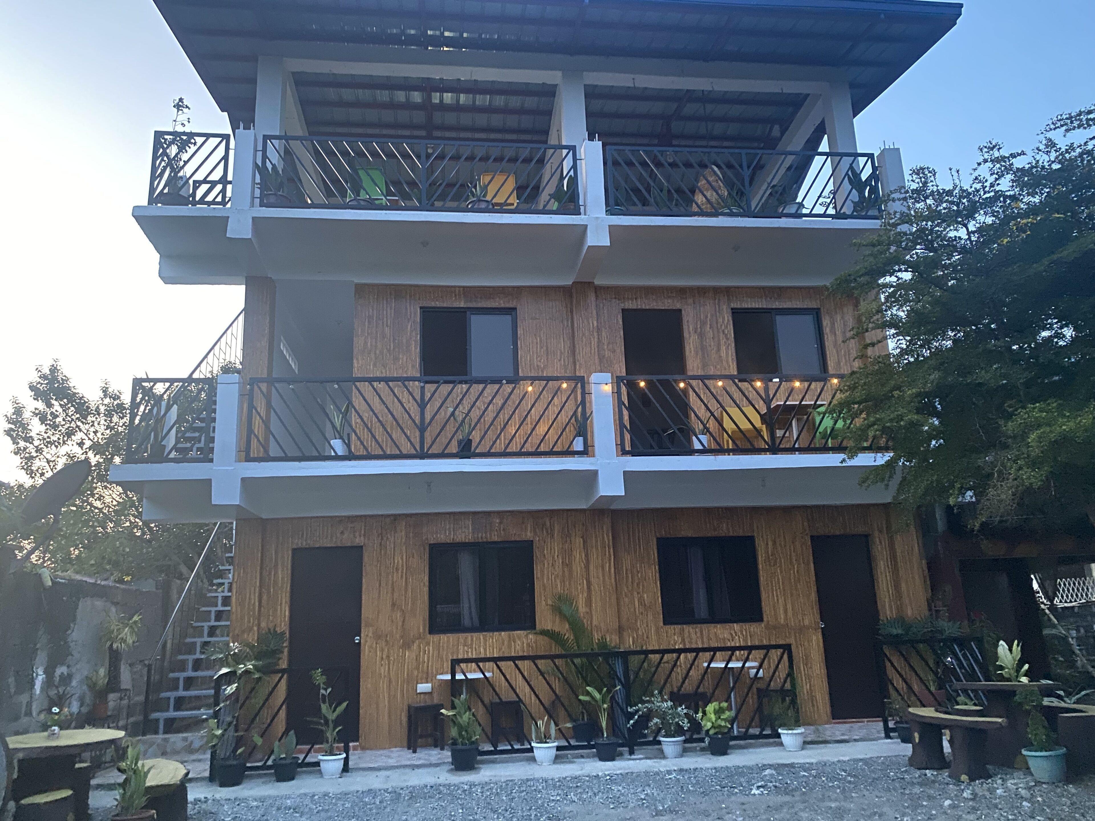 A multi-story building with balconies, potted plants, and outdoor seating.