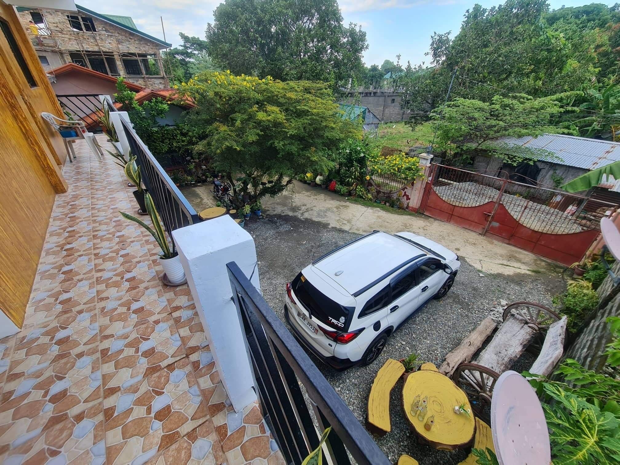 A white car parked in a driveway with a tiled patio and a wooden fence.