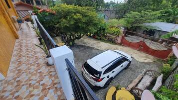 A white car parked in a driveway with a tiled patio and a wooden fence.