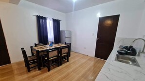 Une cuisine compacte comprenant un évier, un réfrigérateur et un coin repas avec une table et des chaises.