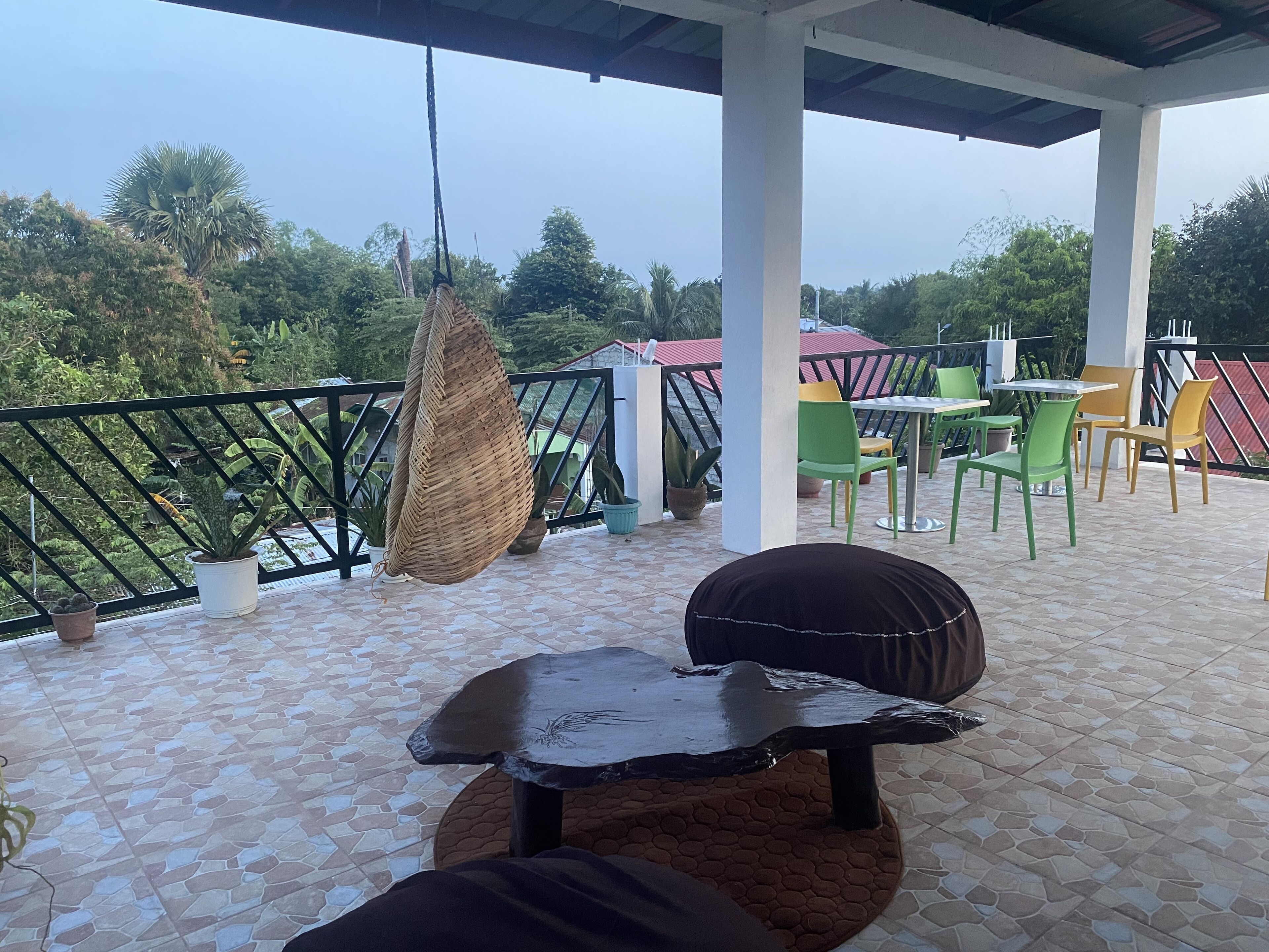 Un espace extérieur abrité, aménagé avec des sièges, une chaise suspendue, une table et des chaises.