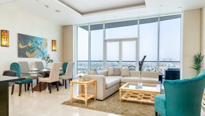 A modern living room with a large window, a sofa, a coffee table, and a dining area with chairs and a table. - Modern, Charming, Sea View Apt. In Palm Jumeirah (Dubai)