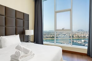 A hotel room with a large bed, a view of a cityscape, and a window with a view of a body of water. - Modern, Charming, Sea View Apt. In Palm Jumeirah (Dubai)