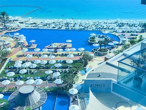 A resort with multiple swimming pools, sun loungers, and umbrellas. - Modern, Charming, Sea View Apt. In Palm Jumeirah (Dubai)