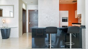 A modern kitchen with a black island, two bar stools, and a microwave. - Modern, Charming, Sea View Apt. In Palm Jumeirah (Dubai)