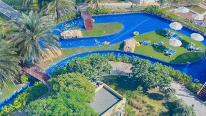 An aerial view of a resort with a large swimming pool, palm trees, and sun loungers. - Modern, Charming, Sea View Apt. In Palm Jumeirah (Dubai)