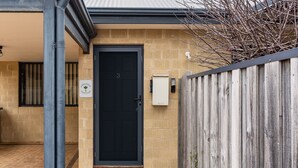 A black door with a sign reading "Lime Tree Cottage" on a beige brick wall.
