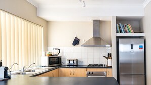A modern kitchen with a central island, stainless steel appliances, and a built-in bookshelf.