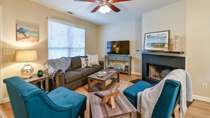 A living room with a ceiling fan, a fireplace, a television, and a sofa. - Lovely home extremely close to Parris Island! (Port Royal)