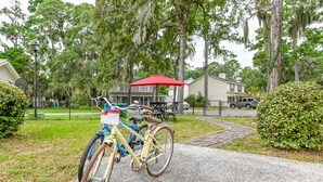 A bicycle parked on a gravel path with a red umbrella nearby, surrounded by greenery and residential houses. - Lovely home extremely close to Parris Island! (Port Royal)