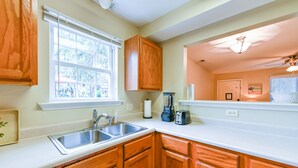 A kitchen with wooden cabinets, a white countertop, a sink, and a window with blinds. - Lovely home extremely close to Parris Island! (Port Royal)