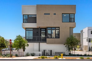 Un bâtiment moderne à plusieurs étages, doté d’un toit plat, de grandes fenêtres et d’un espace de stationnement bien visible, avec un panneau de signalisation et des lampadaires.