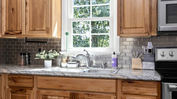 A kitchen with wooden cabinets, a granite countertop, a double sink, a window with a view of trees, and stainless steel appliances. - Home with amazing location, 25min to Wintergreen, 30 min to Charlottesville, 20 min Staunton (Waynesboro)