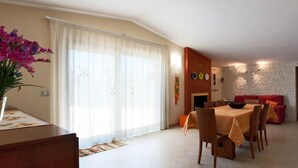 A dining area with a table set for four, a red sofa, and a stone wall. - Villa in Melissano with 4 bedrooms sleeps 8 (Melissano)