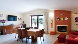A living room with a fireplace, a dining area with a table and chairs, and a red sofa. - Villa in Melissano with 4 bedrooms sleeps 8 (Melissano)