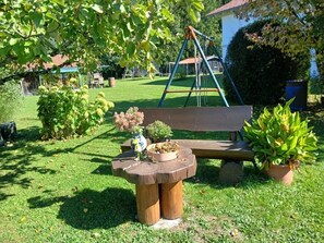 Ein Garten mit einer Schaukel, einer Holzbank und Blumentöpfen.
