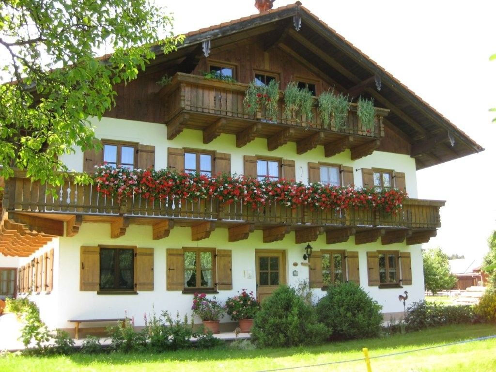 Un chalet traditionnel doté d’un balcon orné de fleurs, de volets en bois et d’un toit à pente.