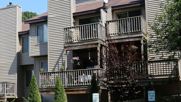 A multi-story residential building with balconies, a stone facade, and a sign indicating reserved parking. - Lakeview Golf Resort Townhouses (Morgantown)