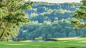 A golf course with a well-maintained green, sand bunkers, and a backdrop of dense forest. - Lakeview Golf Resort Townhouses (Morgantown)