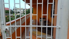 A gated balcony with a view of neighboring buildings and a tiled floor.