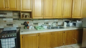 A kitchen with wooden cabinets, a stove, a sink, and various kitchen items.