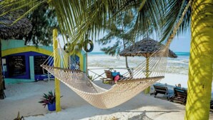 A beach scene with a hammock, lounge chairs, and a thatched-roof structure. - Villa Serenity Zanzibar (Paje)