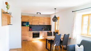 Une cuisine moderne avec des meubles en bois, un coin repas avec une table et des chaises, et un salon avec un canapé et une table basse.