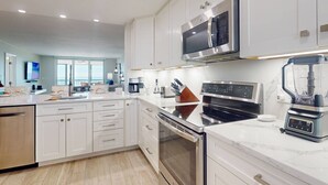 A modern kitchen with white cabinetry, stainless steel appliances, and a central island.