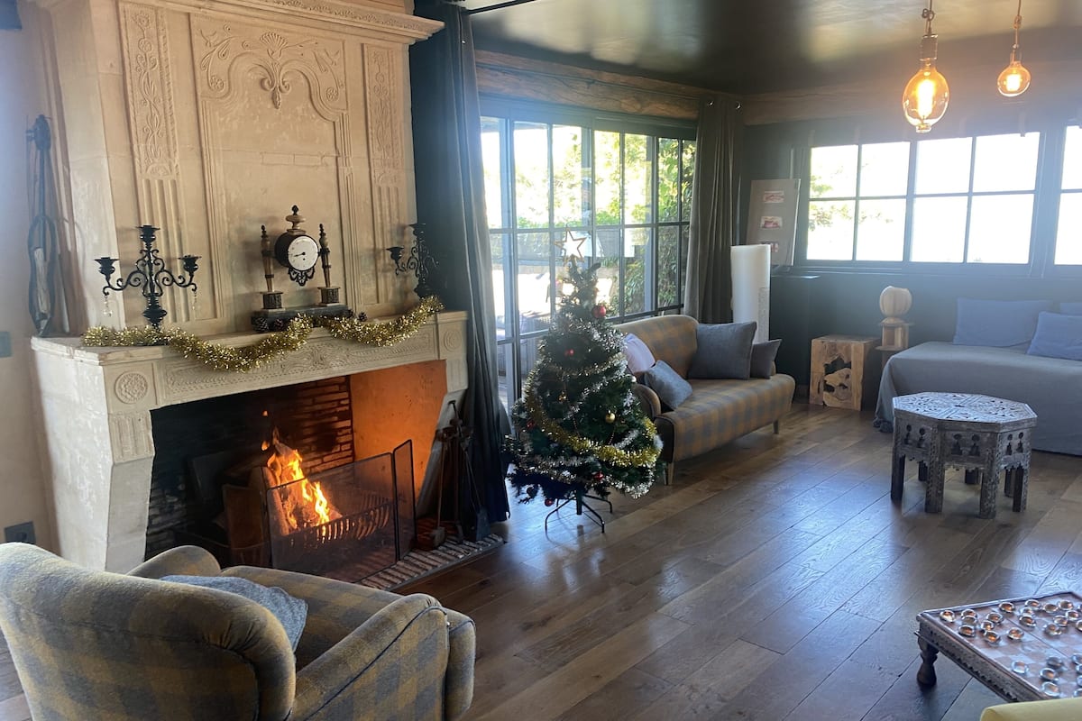 Uma sala de estar acolhedora com lareira, árvore de Natal e um sofá.