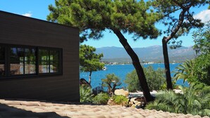 A modern building with a terrace overlooking a coastal area with pine trees and a view of the sea. - Maranatha Porto Vecchio (Porto-Vecchio)