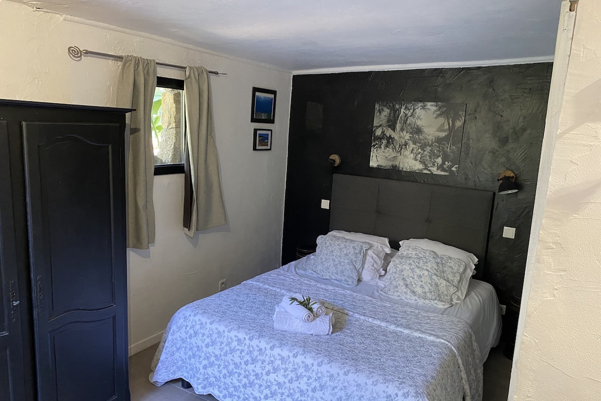 Quarto com cama, guarda-roupa, janela com cortinas e um quadro na parede.