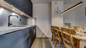 Eine moderne Küche mit Einbauofen, Spüle und Essbereich mit Holzkohle und einem Tisch für zwei Personen.