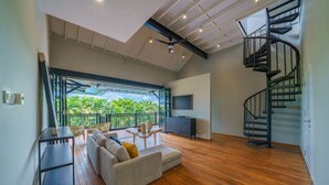 Un salón amplio con piso de madera, un sofá, un televisor y una escalera en espiral.